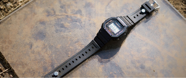一张黑色 G-SHOCK 手表放在地上的照片。