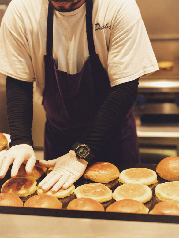 这是一张巴黎 Dumbo Marais 餐厅工作人员手持汉堡餐的照片。