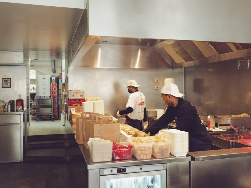 这是一张厨师们在巴黎 Dumbo Marais 餐厅的厨房里制作汉堡的照片。