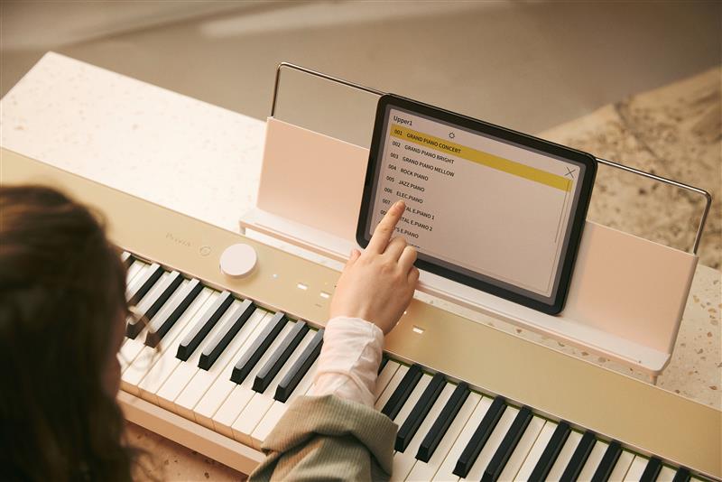 一个人操作连接到钢琴上的平板电脑的图像